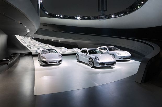 An elliptical ramp leads to the exhibition area displaying the Porsche cars